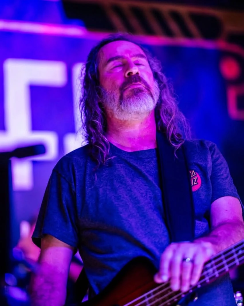 Bass player lost in the song under purple stage lights