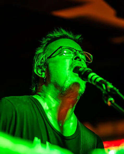 Crow singing at the mic in green stage light